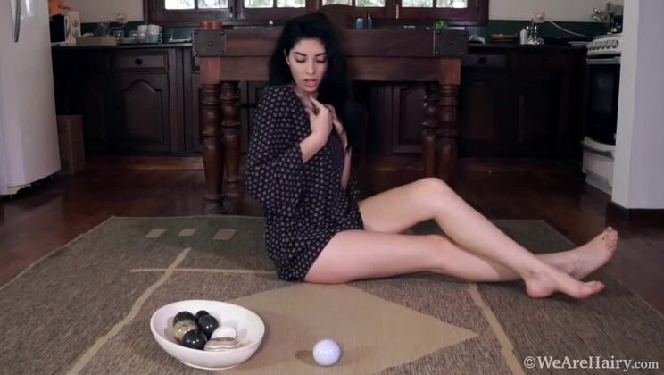 Hairy brunette Ornella rubs stones on her pussy